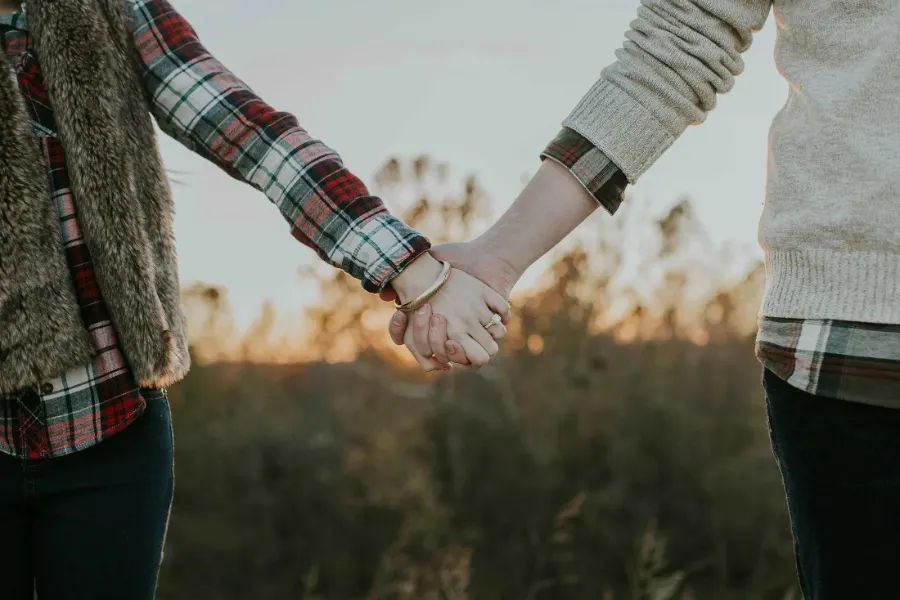 A couple holding hands outdoors at sunset