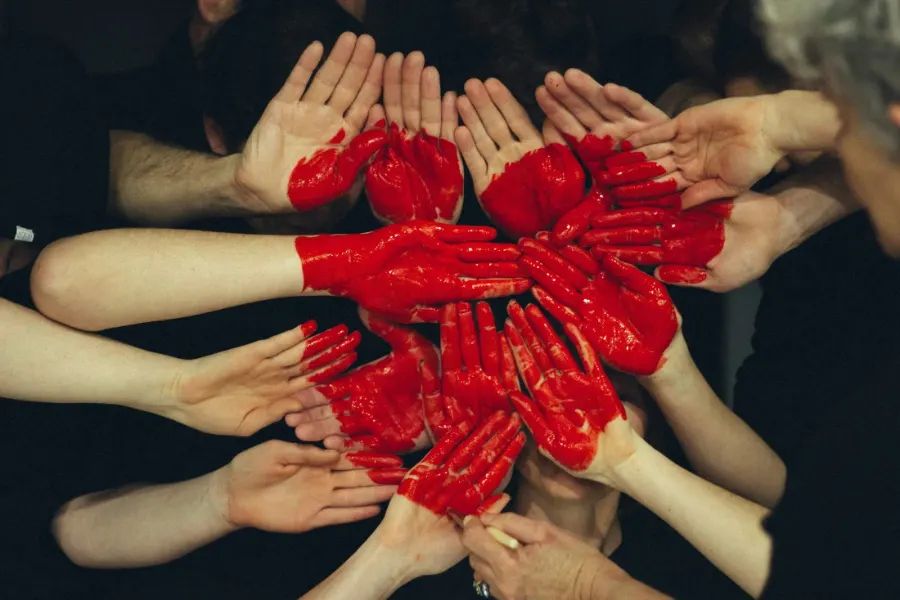 Many hands together around a red heart